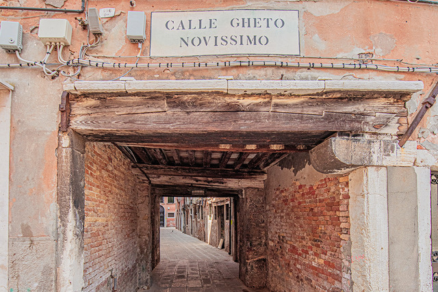 cobblestoned street with a low arch, with a phrase written in italian