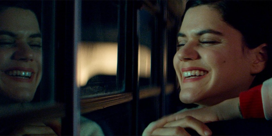 A photo of a woman laughing in front of a window