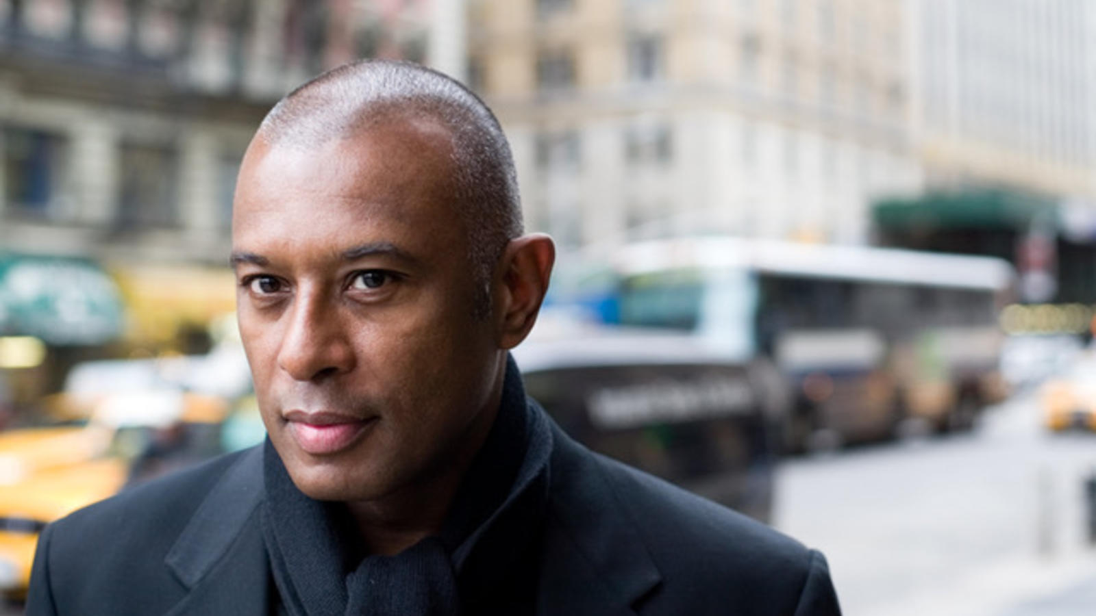 a bald black man outside on a new york street, looking directly into the camera