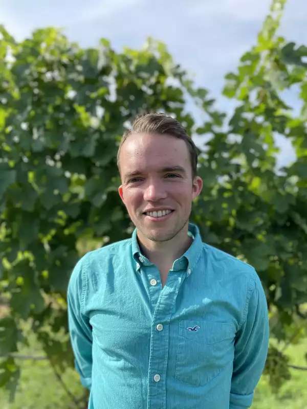 a white man standing outside looking directly into the camera and smiling.